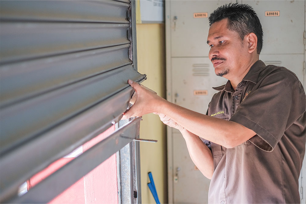 Technician repairing a metal roller shutter.