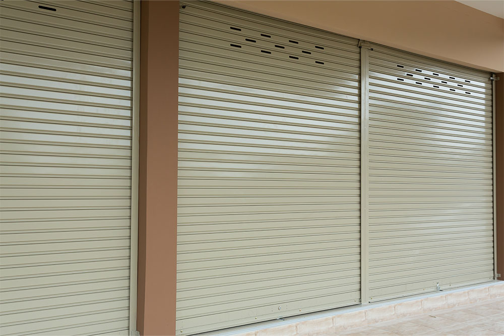 Grey steel roller shutter installed on shopfront exterior. 