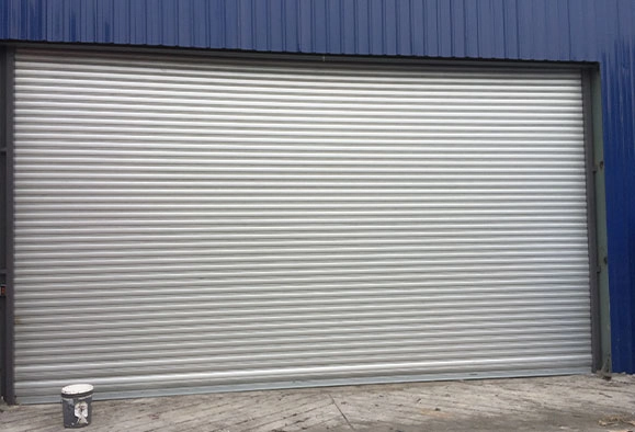 A closed zincalume roller shutter covering a large entrance to a warehouse
