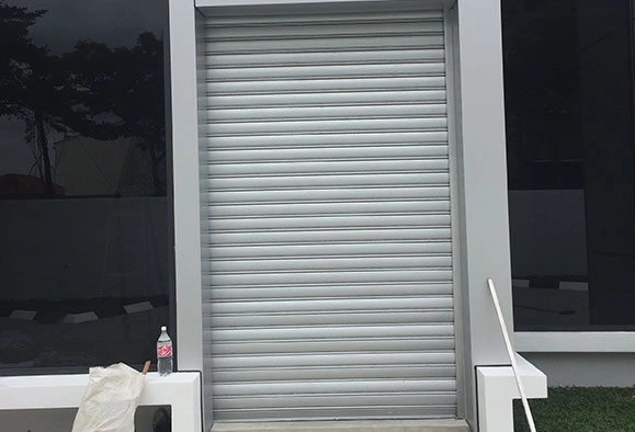 A closed gray zincalume roller shutter covering an entrance